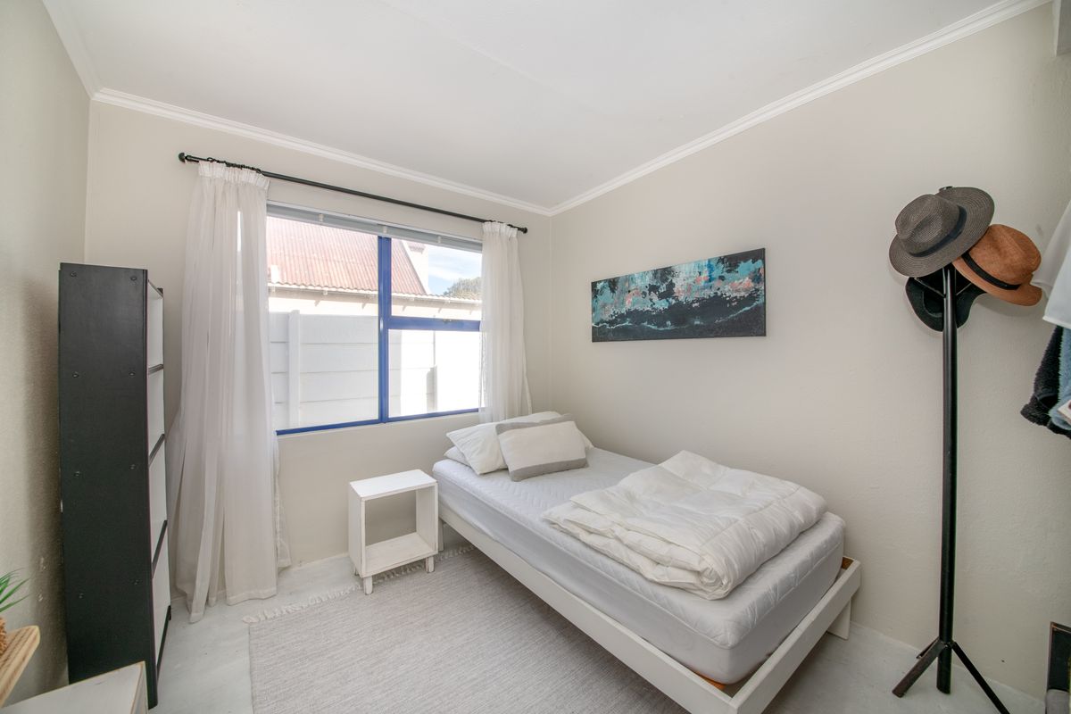 A compact bedroom featuring neutral wall tones, a window with natural light, and simple crown molding.