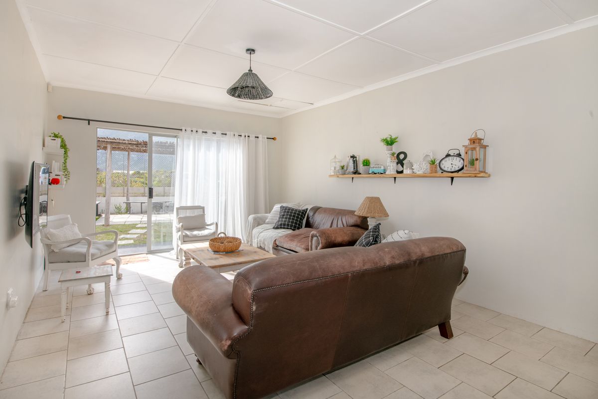 A bright living room featuring tiled flooring and a sliding glass door providing direct access to the outdoor patio area.