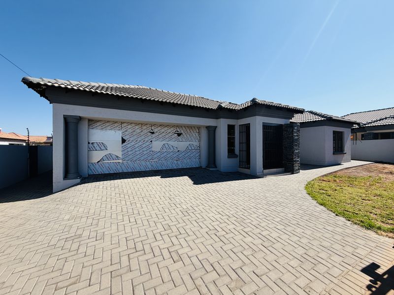 Modern front elevation featuring a paved driveway, double garage with protective film still attached, and stone cladding accents.