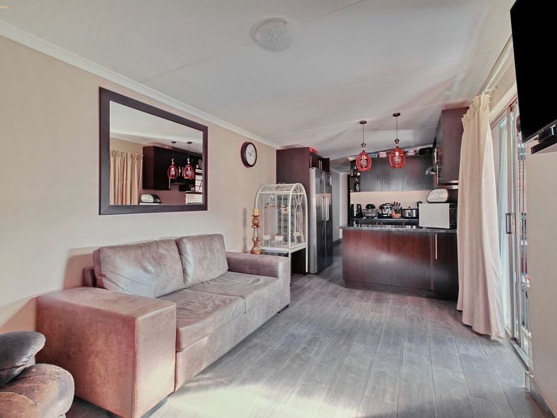 Open-plan living area featuring a kitchen with dark cabinetry and a breakfast island, seamlessly connected to a lounge space with sliding door access.