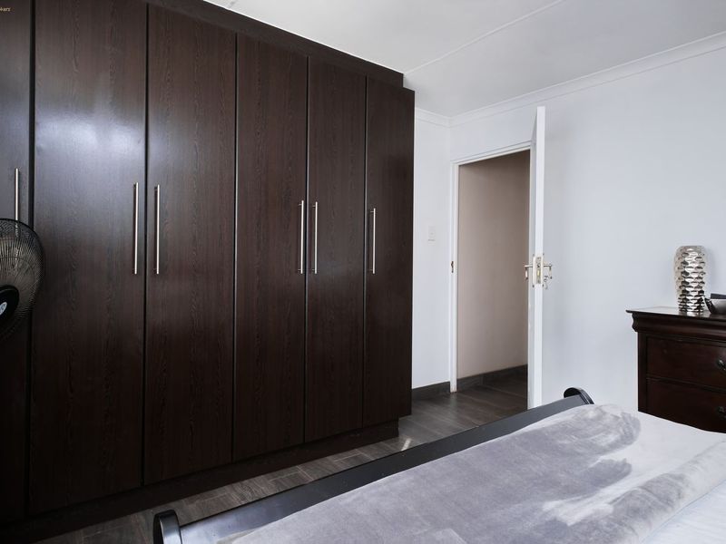 A bedroom featuring dark wood built-in cupboards and neutral wall finishes.