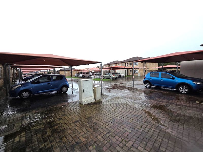 Exterior view of the apartment complex parking area featuring paved driveways and covered shade cloth parking bays.