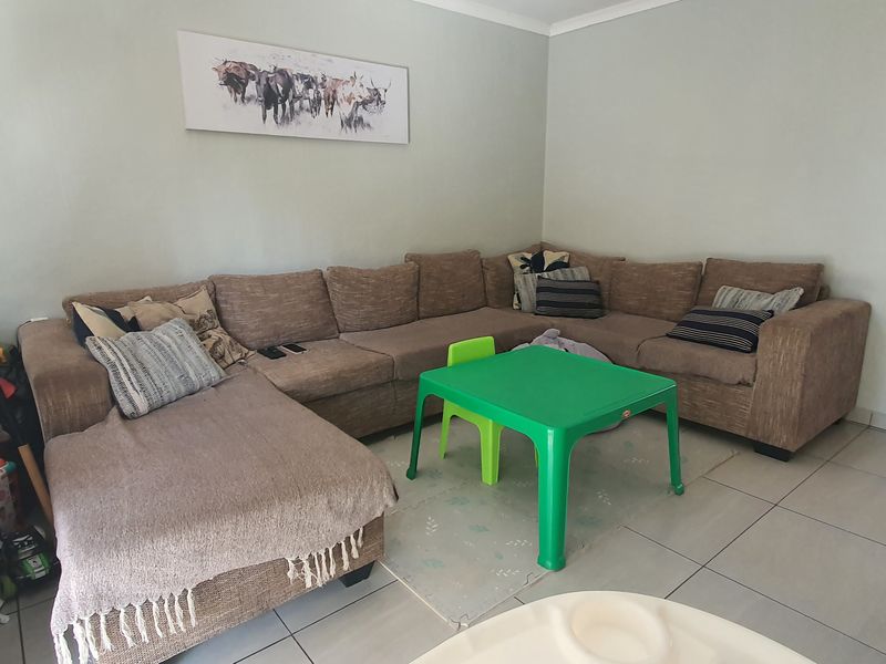 A living room featuring neutral wall tones, tiled flooring, and cove cornicing, providing a functional base for a comfortable family space.