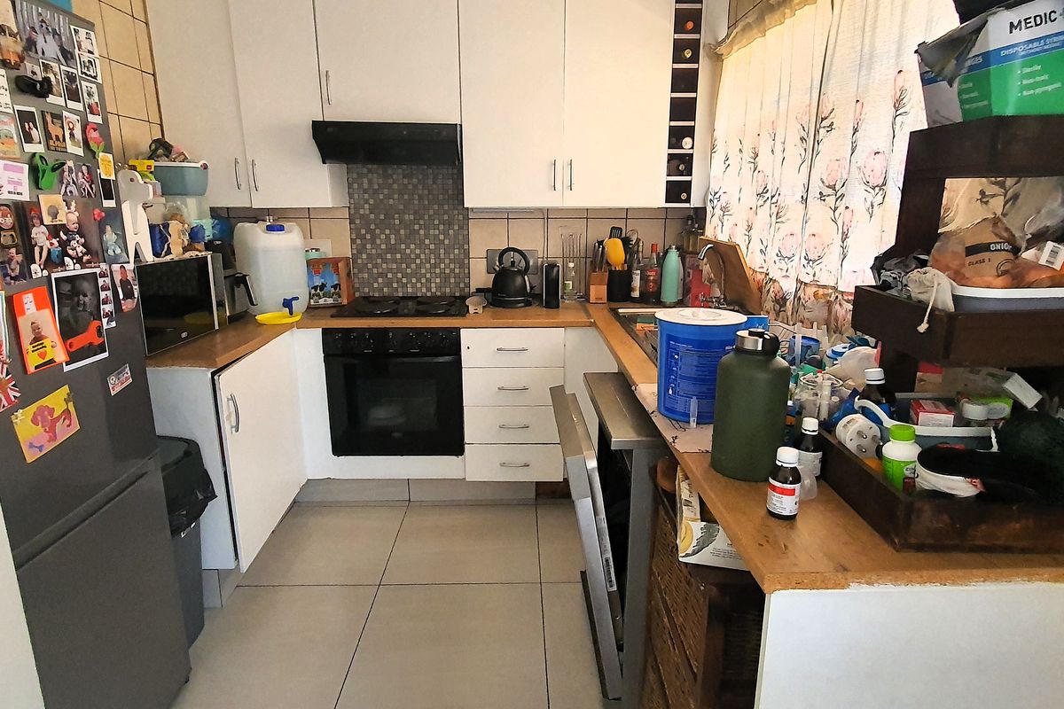 A functional kitchen featuring built-in cabinetry, a tiled splashback, and integrated oven and hob, offering a practical layout for daily meal preparation.