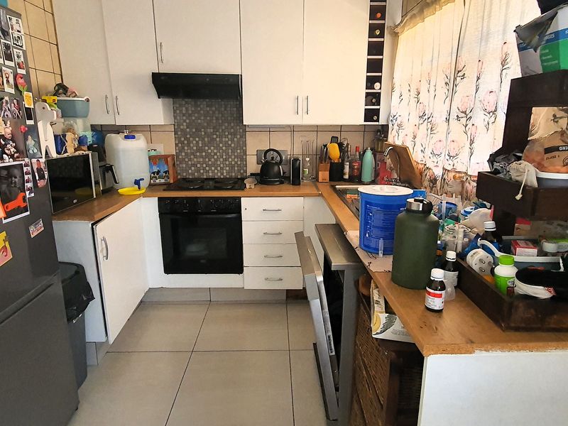 A functional kitchen featuring built-in cabinetry, a tiled splashback, and integrated oven and hob, offering a practical layout for daily meal preparation.