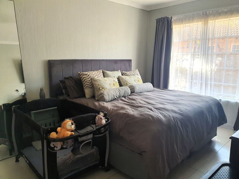 A bedroom featuring tiled flooring and a built-in cupboard, with natural light entering through a window dressed with curtains.