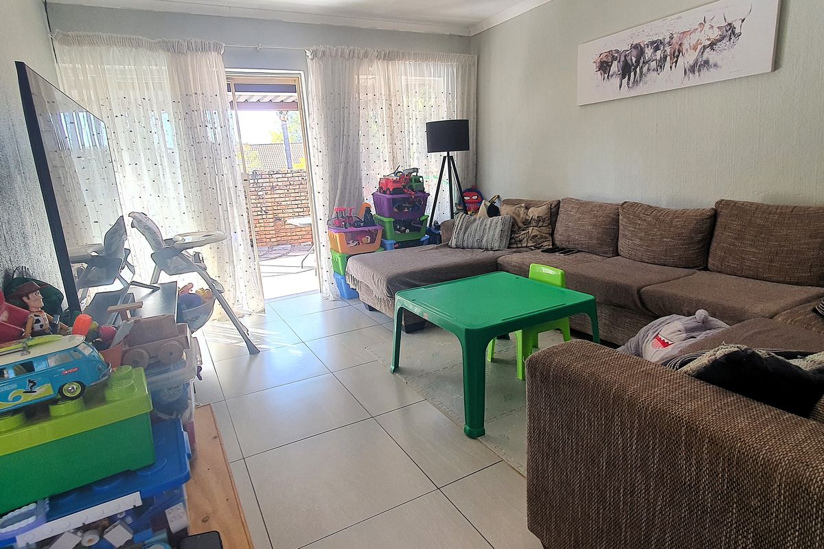 A living room featuring tiled flooring and a sliding glass door providing access to the outdoor patio area.