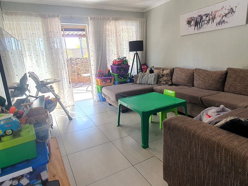 A living room featuring tiled flooring and a sliding glass door providing access to the outdoor patio area.