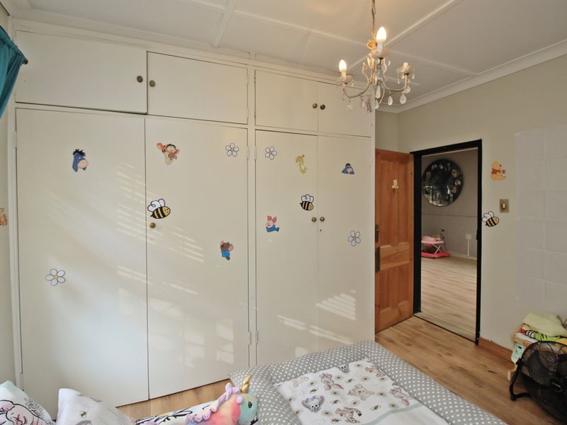 Bedroom featuring extensive built-in storage cupboards, laminate flooring, and a decorative ceiling chandelier.