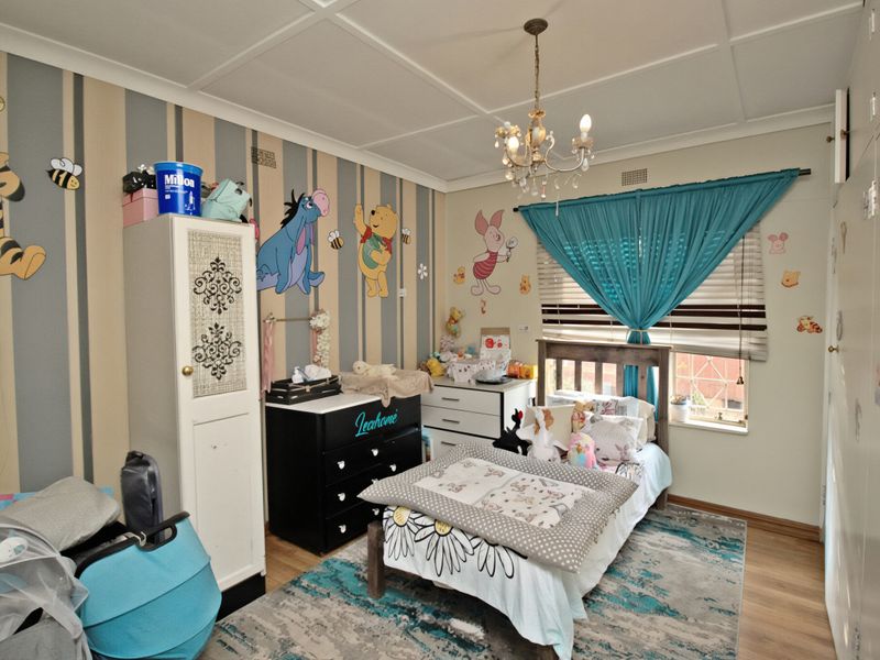 A bedroom featuring laminate flooring, a built-in cupboard, and a decorative chandelier, currently styled as a child's room.