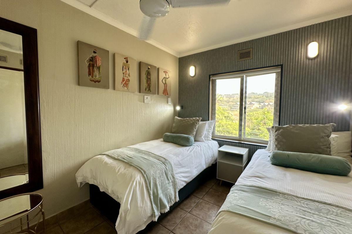 A compact bedroom featuring tiled flooring, a ceiling fan, and a window with natural light, finished with textured wall treatments.