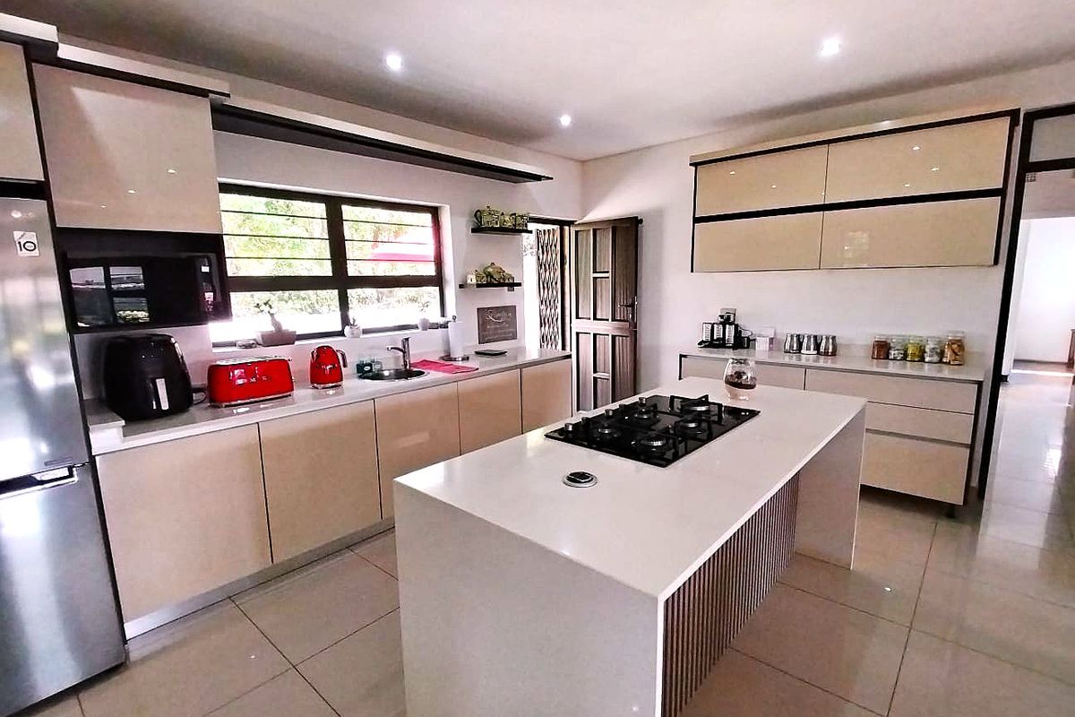 Modern kitchen featuring a central island with a gas cooktop, sleek cabinetry, stone countertops, and high-quality tiled flooring.