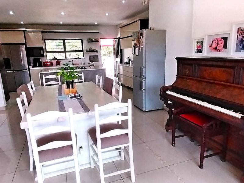 Spacious open-plan living and dining area featuring tiled floors, recessed lighting, and a modern kitchen with integrated cabinetry and island.