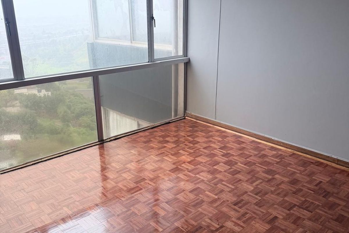 An empty bedroom featuring polished parquet flooring and large windows offering an elevated view.