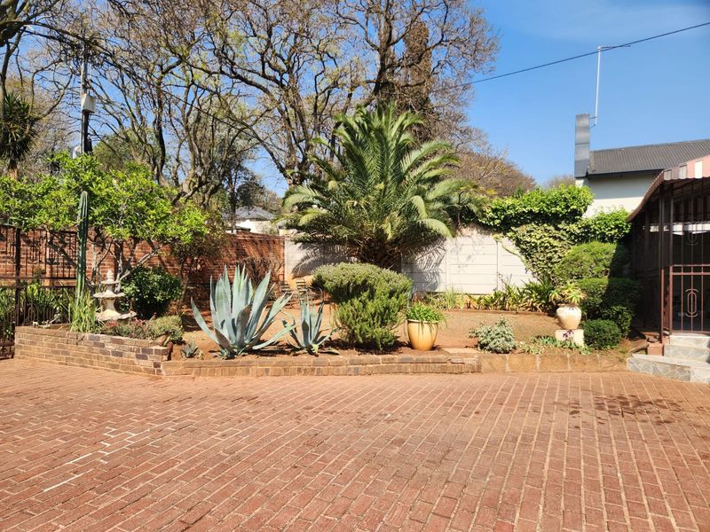 A well-established rear garden featuring a brick-paved patio area, mature landscaping, and a brick retaining wall, providing a private outdoor space.