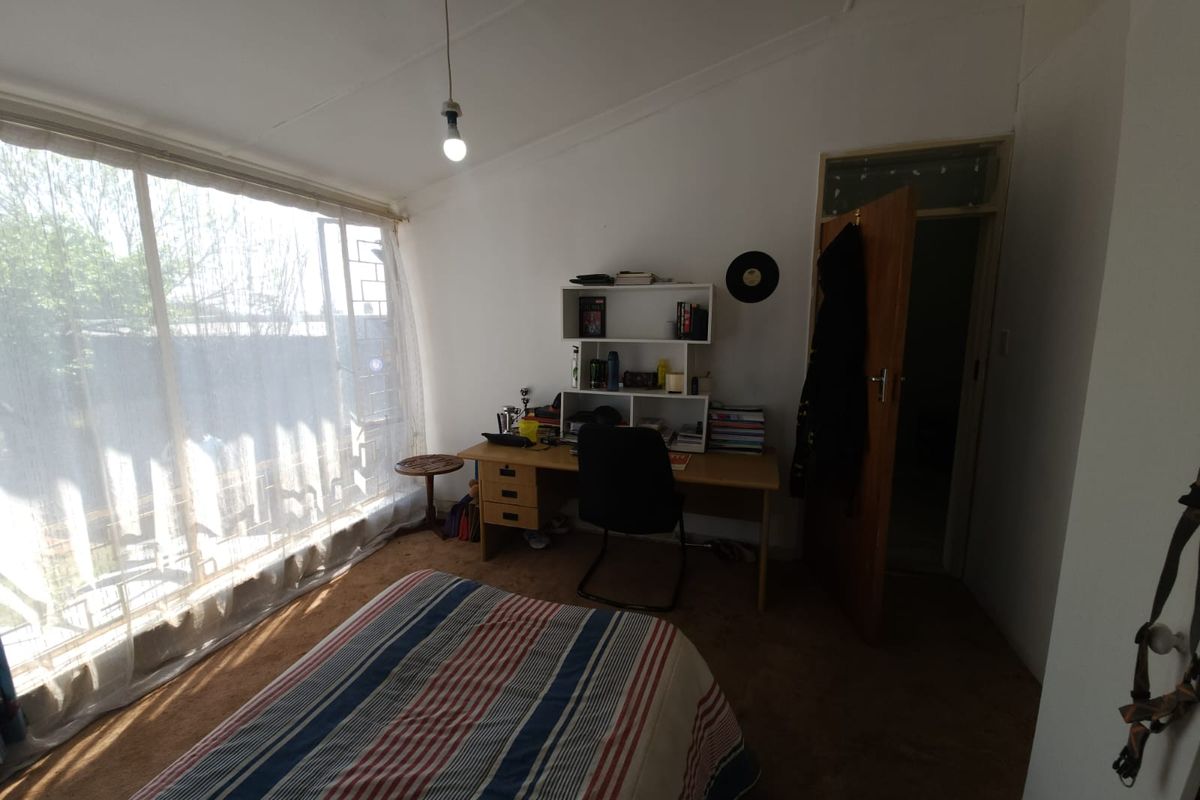 A bedroom featuring large windows allowing natural light, carpet flooring, and direct access to an adjoining room.
