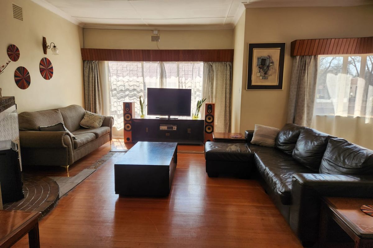 Spacious living room featuring polished hardwood flooring, a fireplace, and classic cornice detailing, offering a comfortable and traditional atmosphere.