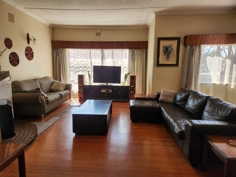 Spacious living room featuring polished hardwood flooring, a fireplace, and classic cornice detailing, offering a comfortable and traditional atmosphere.