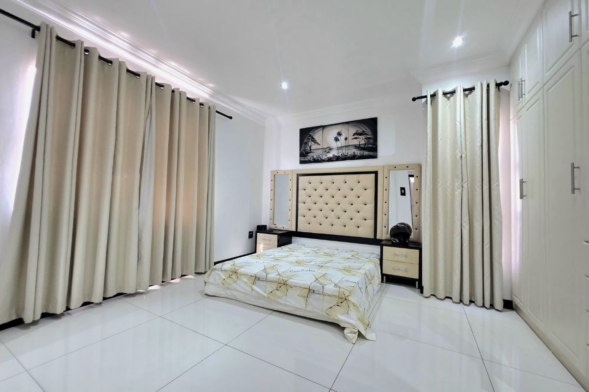 A well-maintained bedroom featuring large format floor tiles, built-in cabinetry, and decorative ceiling moulding with recessed lighting.