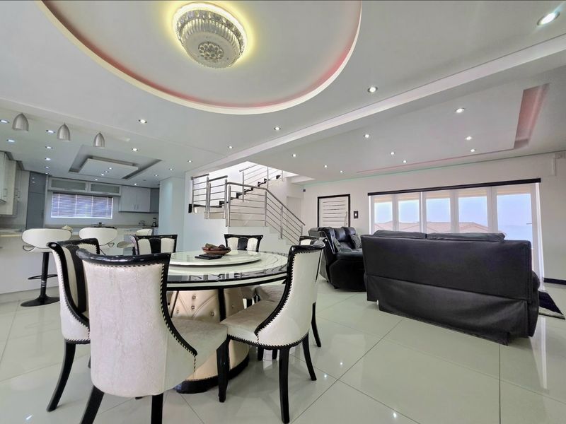 Spacious open-plan living and dining area featuring modern recessed ceiling lighting, tiled floors, and a contemporary staircase with a stainless steel balustrade.