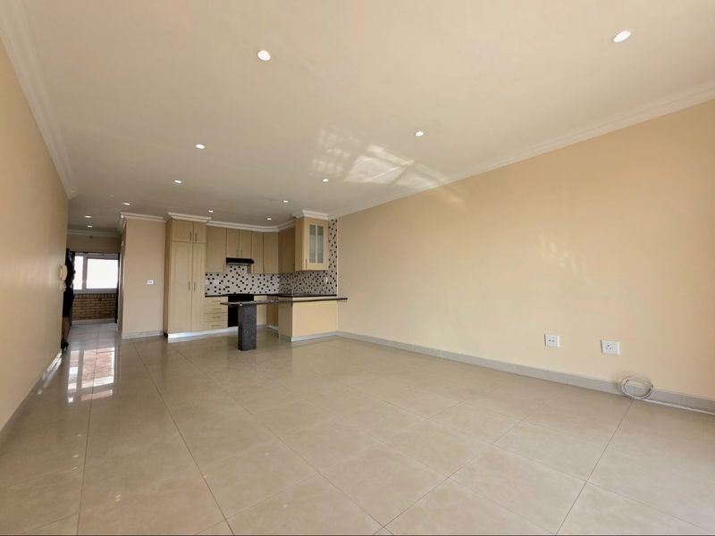 Spacious open-plan living area featuring tiled floors, recessed lighting, and a functional kitchen with built-in cabinetry and a breakfast bar.