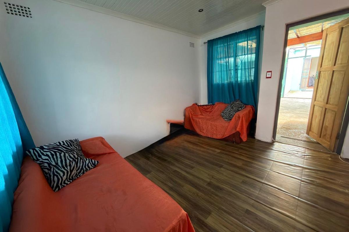 A bedroom featuring laminate flooring and a timber door leading to an outdoor area.