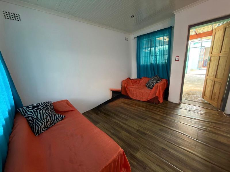 A bedroom featuring laminate flooring and a timber door leading to an outdoor area.
