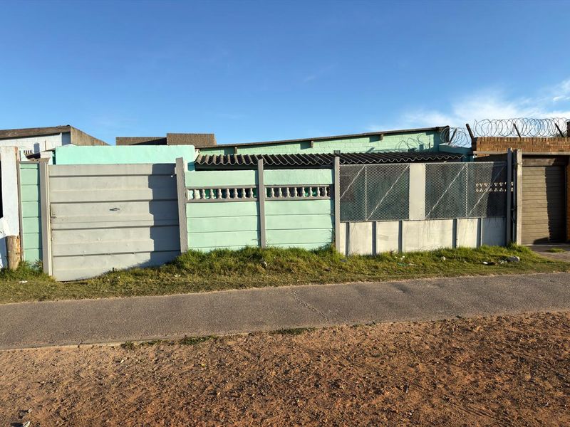 Front exterior view of the property featuring a precast concrete boundary wall, metal gate, and security razor wire.