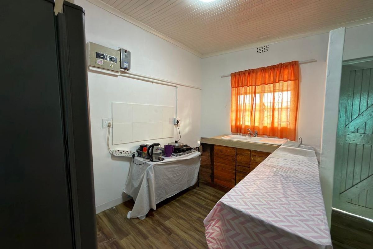 A functional kitchen area featuring a double sink, wooden cabinetry, and timber-look flooring, with potential for modernization and improved layout.
