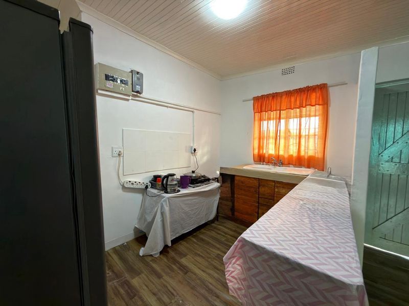 A functional kitchen area featuring a double sink, wooden cabinetry, and timber-look flooring, with potential for modernization and improved layout.