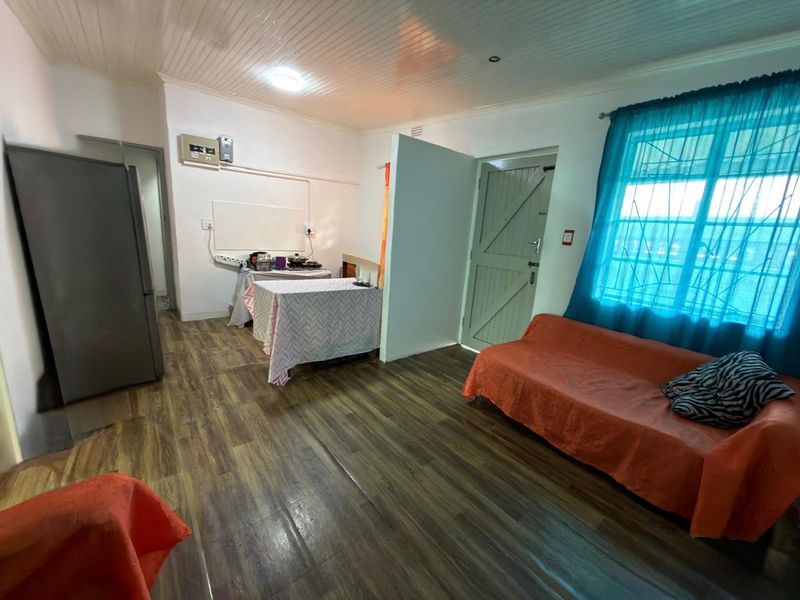 Open-plan living area featuring wood-look laminate flooring, tongue and groove ceiling, and a secure entrance door.