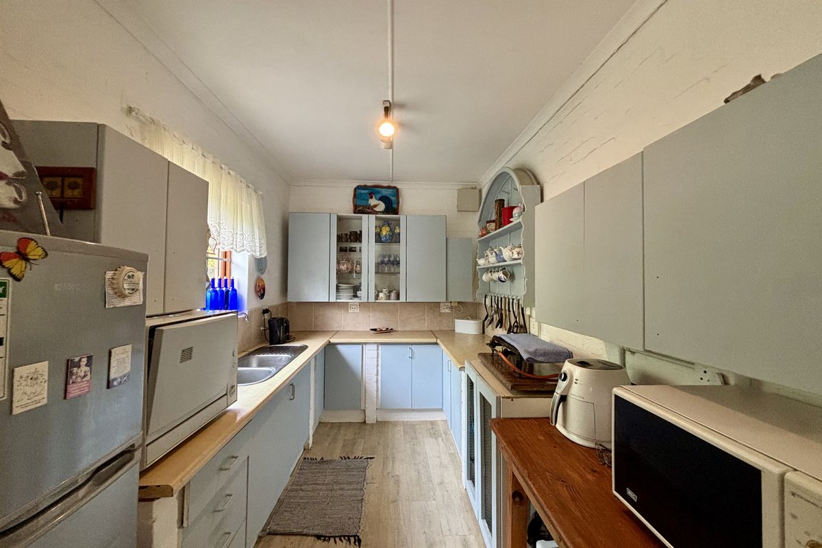 A functional kitchen featuring light blue built-in cabinetry, tiled backsplash, double basin sink, and wood-look laminate flooring.