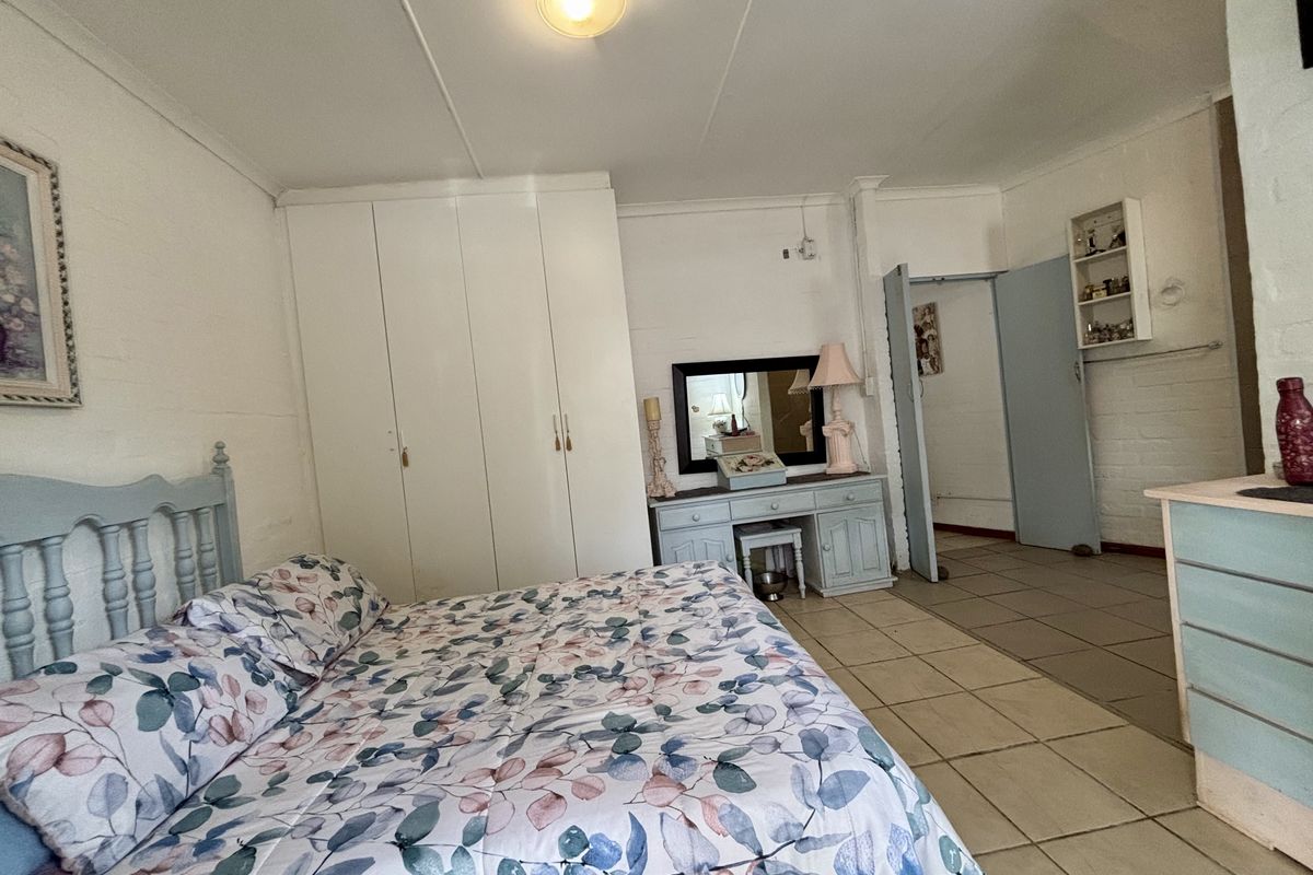 A bedroom featuring built-in cupboards, tiled flooring, and built-in shelving, with visible ceiling panel damage.