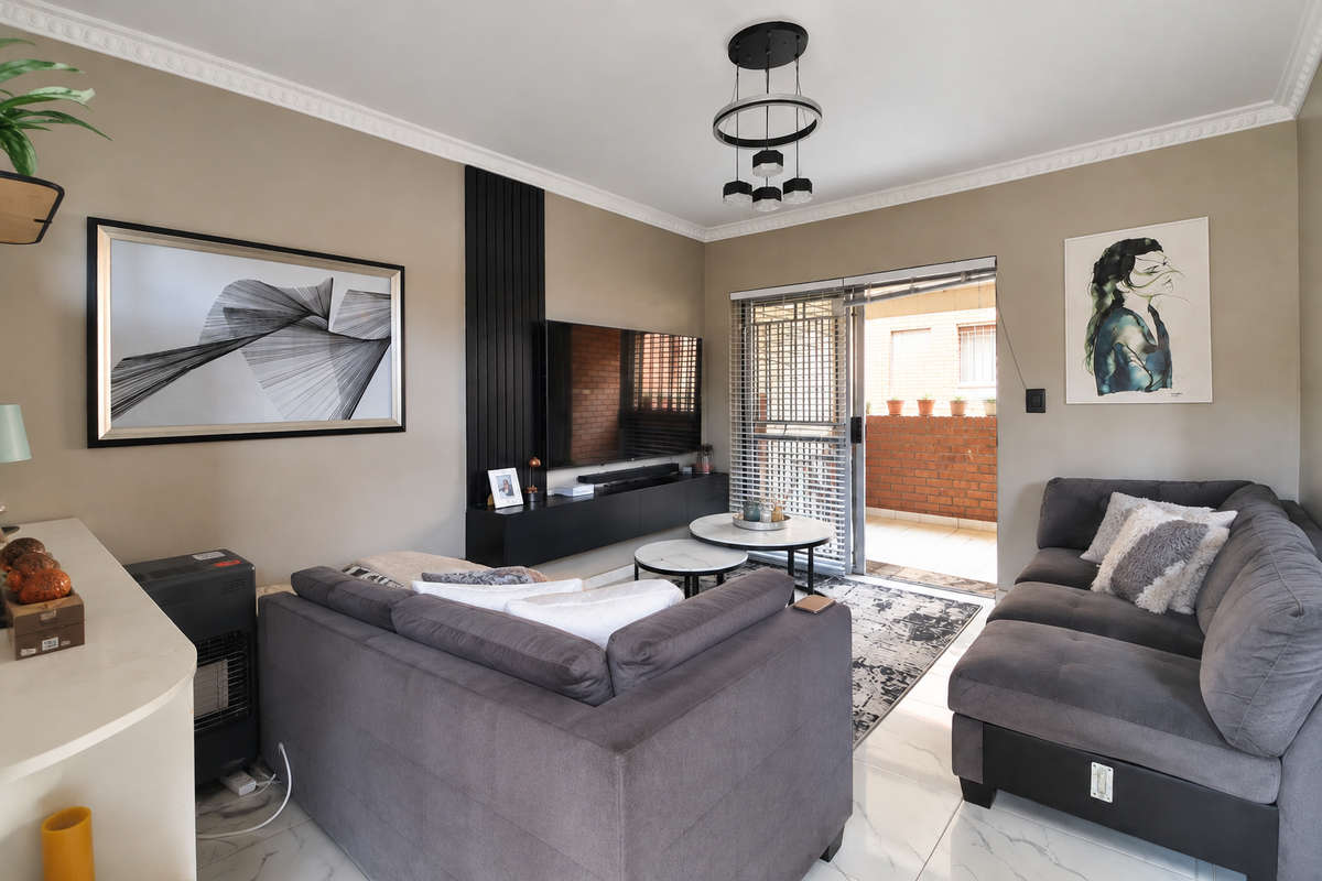 A well-maintained living room featuring modern crown molding, a sleek built-in media console with slatted wall detailing, and direct access to a private patio.