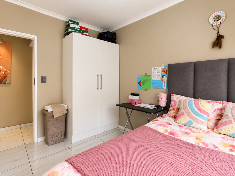 A well-maintained bedroom featuring tiled flooring, neutral wall tones, and a built-in wardrobe, providing a functional and comfortable living space.