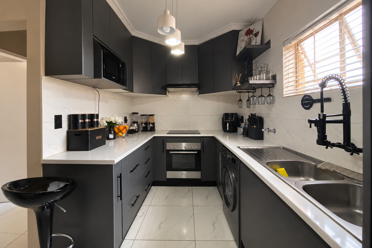 Modern U-shaped kitchen featuring dark cabinetry, white quartz countertops, integrated appliances, and high-quality porcelain tile flooring with a sleek contemporary finish.