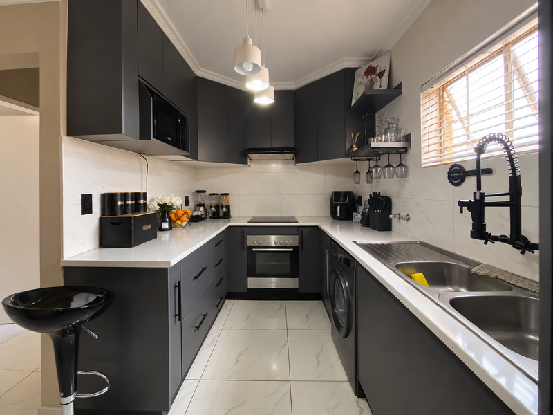 Modern U-shaped kitchen featuring dark cabinetry, white quartz countertops, integrated appliances, and high-quality porcelain tile flooring with a sleek contemporary finish.