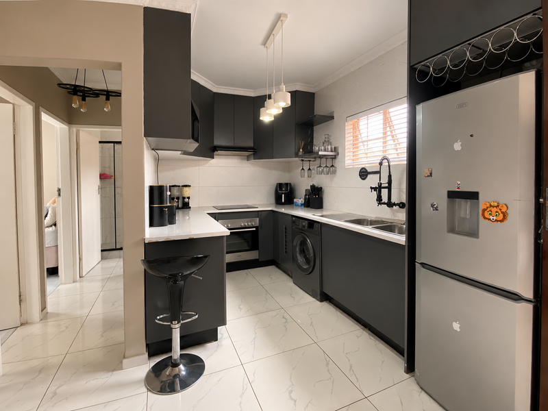 Modern kitchen featuring dark cabinetry, stone countertops, integrated appliances, and sleek tiled flooring, offering a functional and contemporary cooking space.