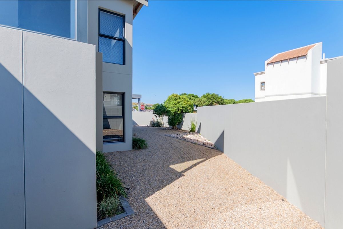 A clean and well-maintained side garden area featuring gravel landscaping and high boundary walls, providing a private outdoor space.