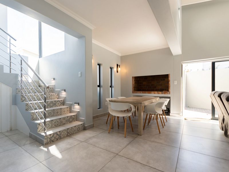 Open plan living area featuring a modern staircase with decorative tile risers, stainless steel balustrades, built-in fireplace, and large format ceramic floor tiles.