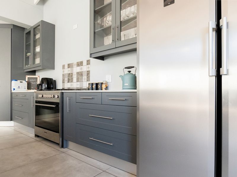 Modern kitchen featuring sleek grey cabinetry, stainless steel appliances, stone countertops, and a decorative tiled backsplash, offering a clean and contemporary aesthetic.