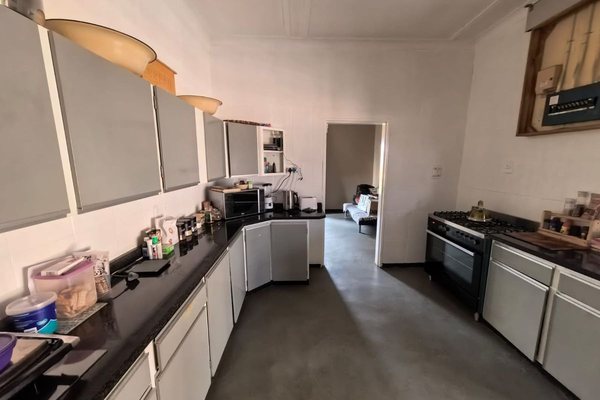 A functional kitchen featuring built-in cabinetry, granite countertops, and a gas stove, requiring cosmetic updates to the walls and electrical housing.