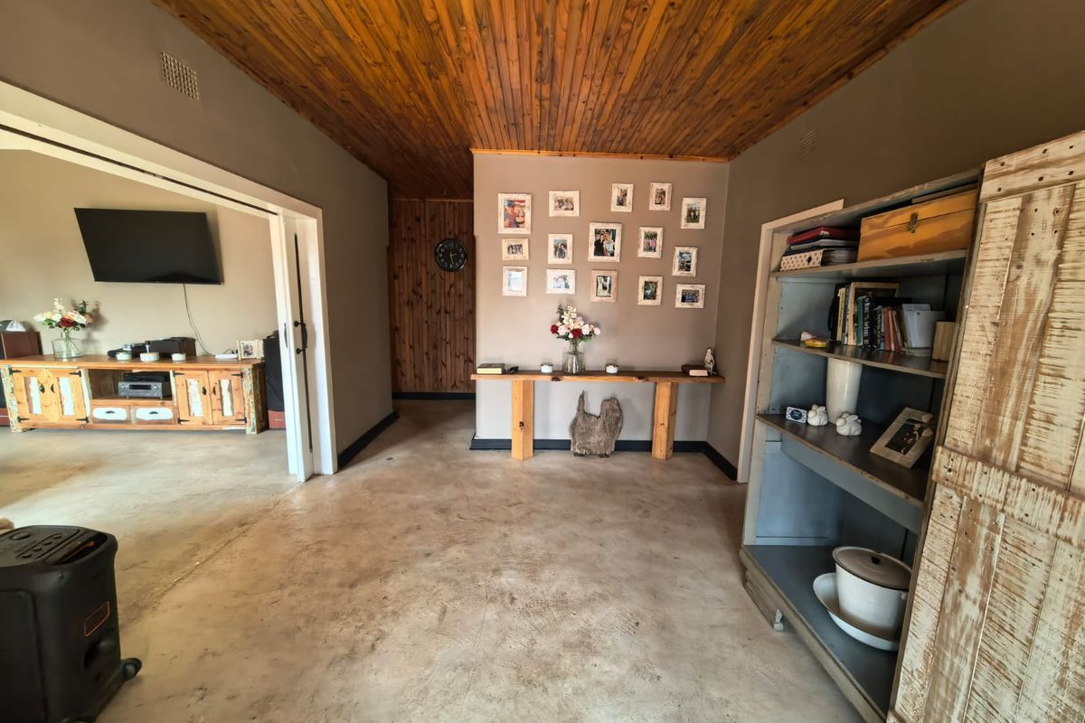 Spacious living area featuring a warm timber tongue and groove ceiling, polished concrete floors, and rustic timber wall accents.
