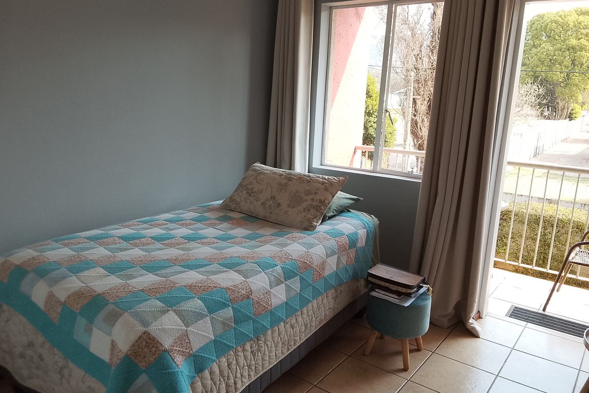 A bedroom featuring tiled flooring, large windows, and direct access to a private balcony, providing natural light and outdoor connectivity.
