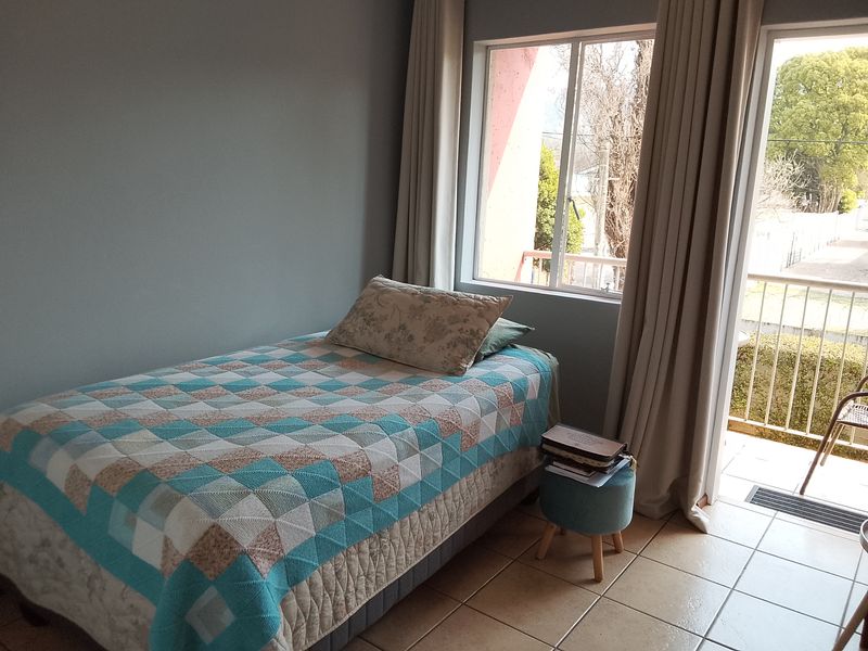 A bedroom featuring tiled flooring, large windows, and direct access to a private balcony, providing natural light and outdoor connectivity.