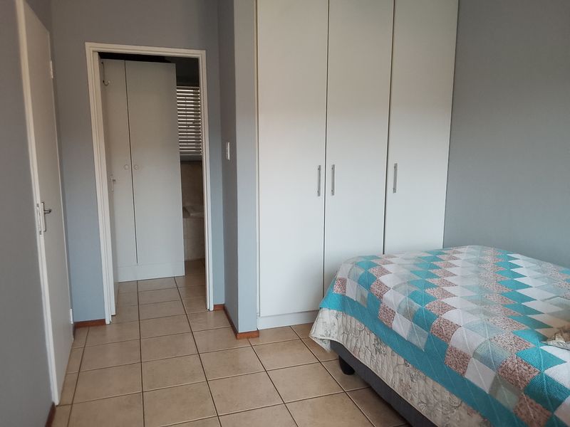 A bedroom featuring built-in cupboards, tiled flooring, and an adjoining en-suite bathroom.