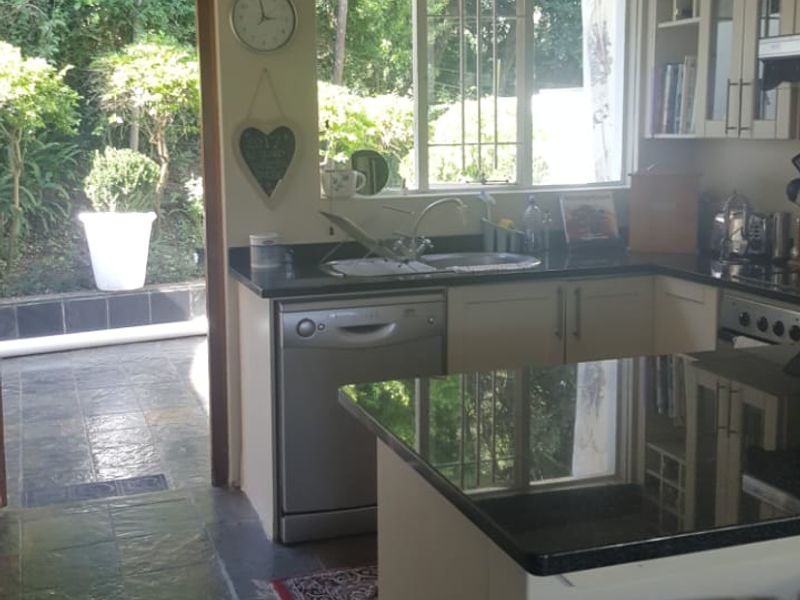 A functional kitchen featuring granite countertops, built-in cabinetry, and a kitchen island, with direct access to an outdoor patio area.