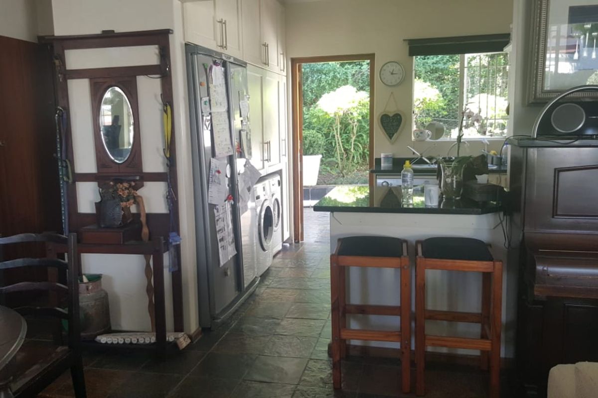 A functional kitchen area featuring built-in cabinetry, stone countertops, and a breakfast bar, with direct access to the outdoor garden space.