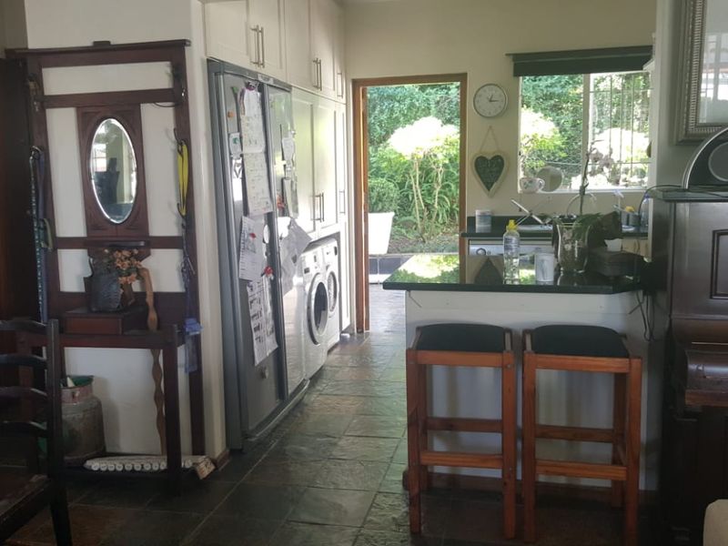A functional kitchen area featuring built-in cabinetry, stone countertops, and a breakfast bar, with direct access to the outdoor garden space.