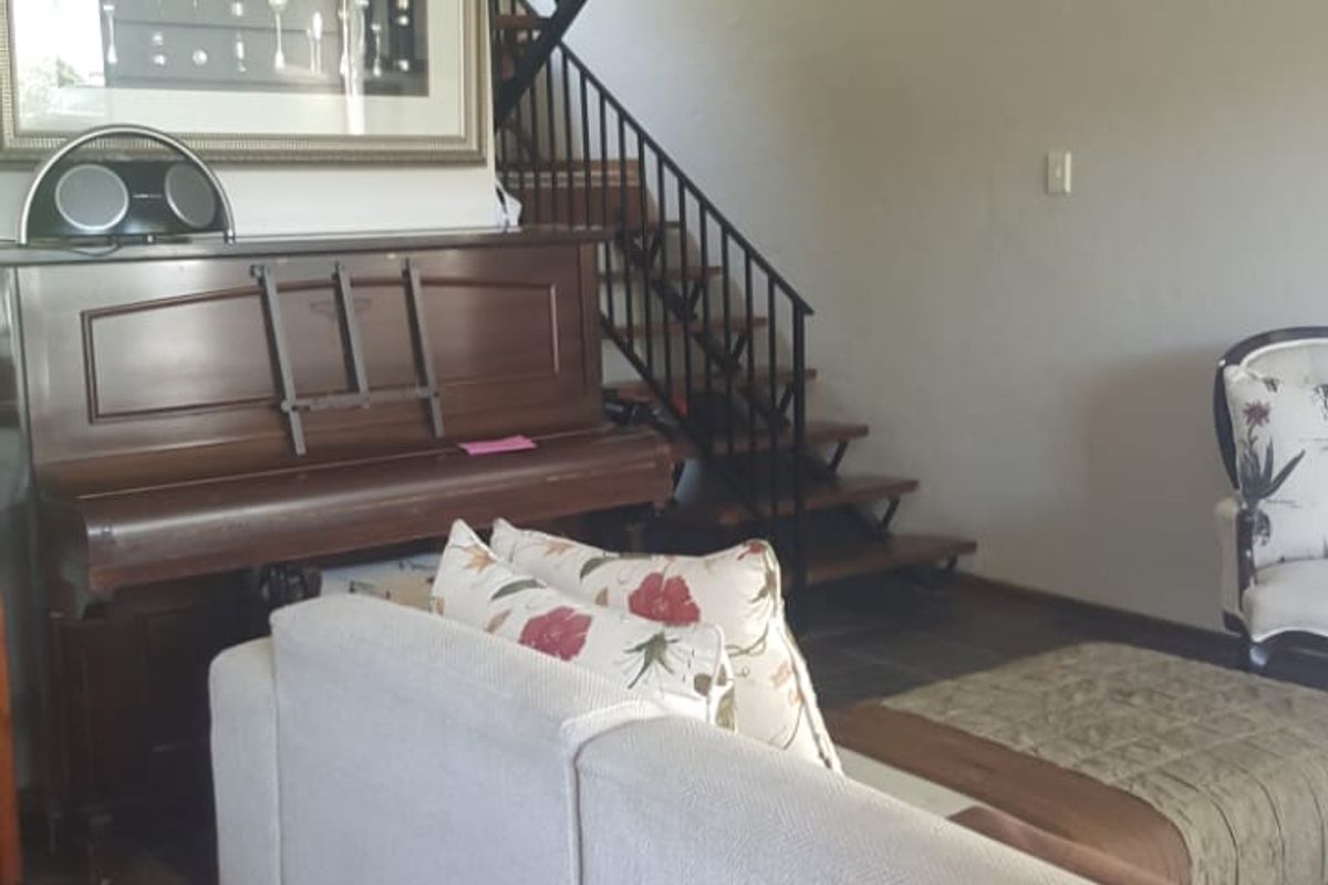 Living room featuring slate tile flooring and an open-tread staircase with a wrought iron balustrade.